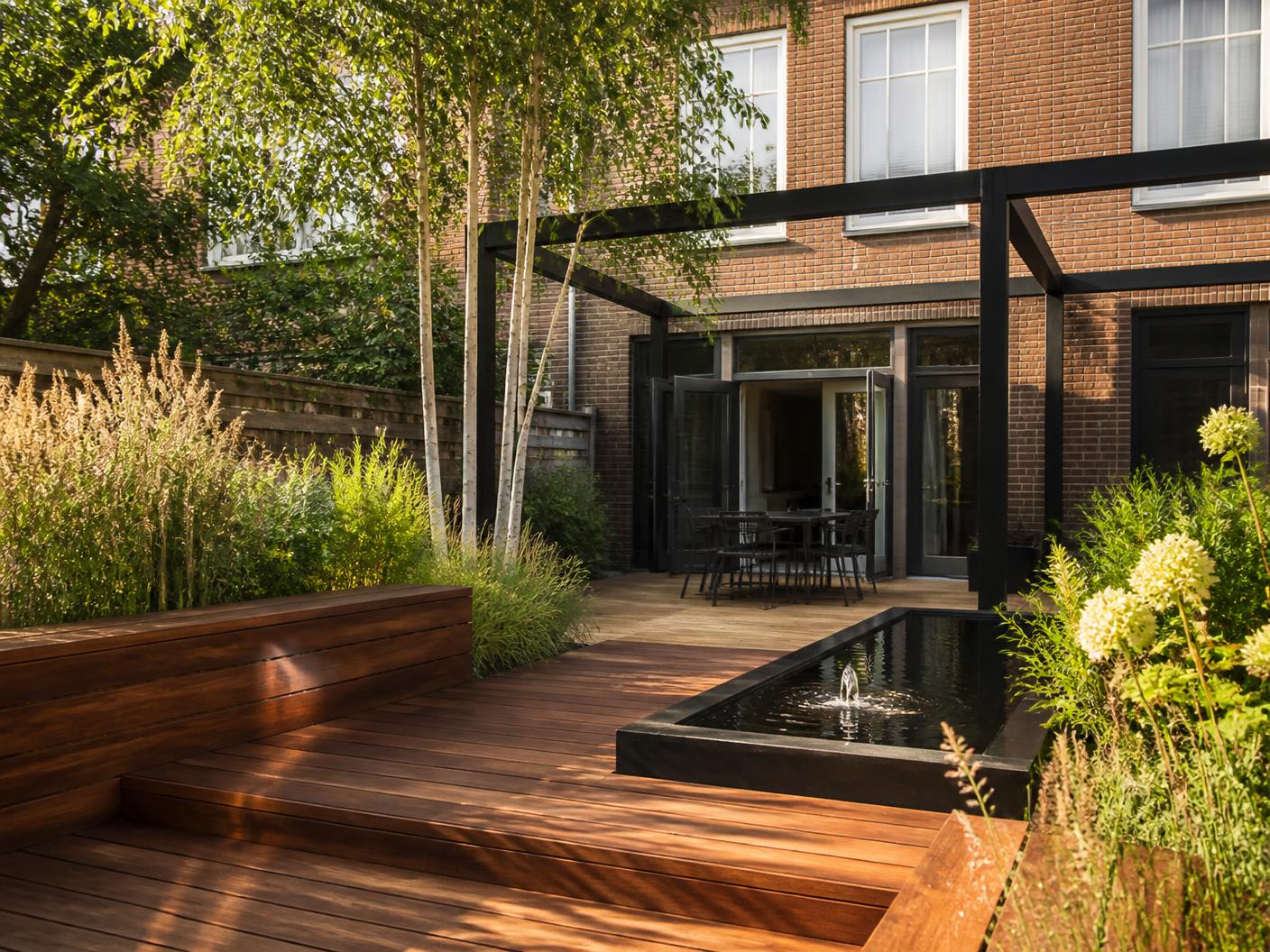 Moderne stadstuin in Rotterdam met hardhouten vlonder, zwarte stalen pergola en waterelement
